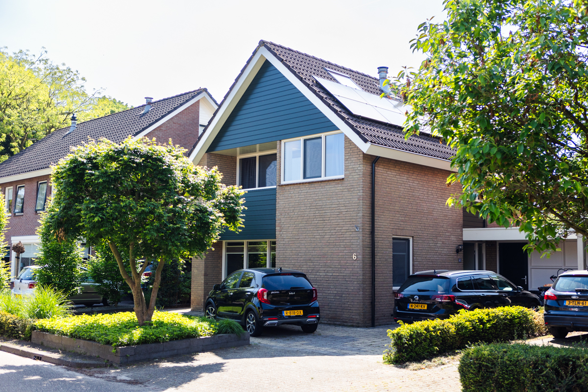 Voorgevel van een gerenoveerde woning met kunststof kozijnen: vaste delen in RAL 9001 en draaideelkozijnen in nerfstructuur RAL 6009, afgewerkt met bijpassende gevelbekleding