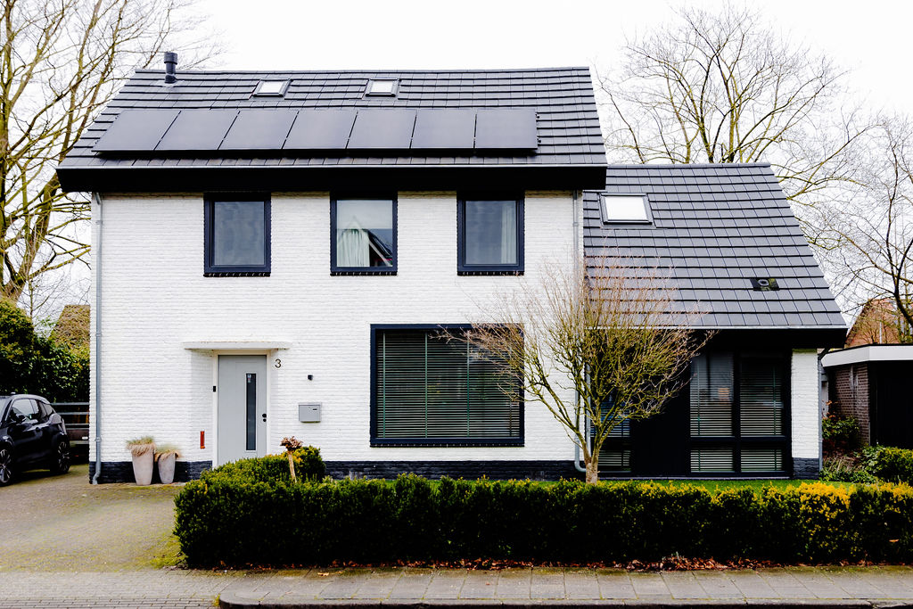Voorgevel van een moderne woning met strakke kunststof kozijnen in diepe antracietkleur (RAL 7016).
