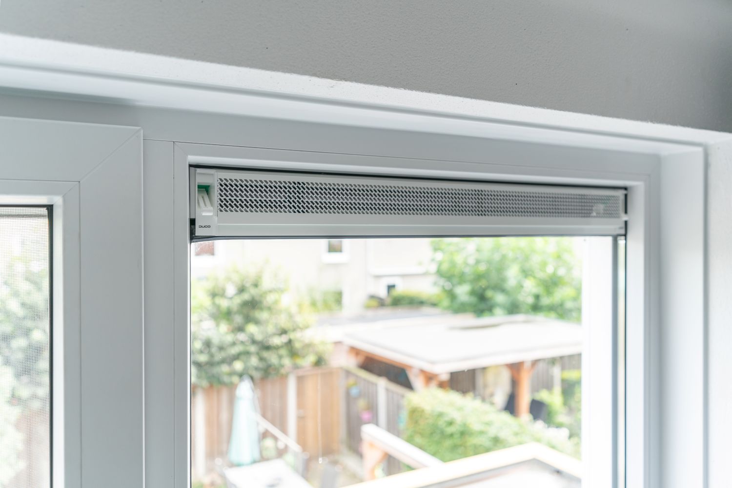 Ventilatierooster geïntegreerd in een wit kunststof kozijn