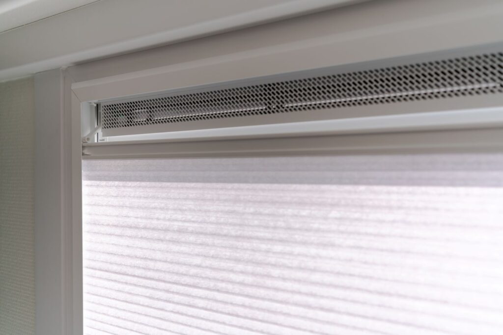 Binnenzicht van een kunststof kozijn in RAL 9016 met ventilatierooster en Splendid binnenzonwering, voor lichtregeling en comfort.